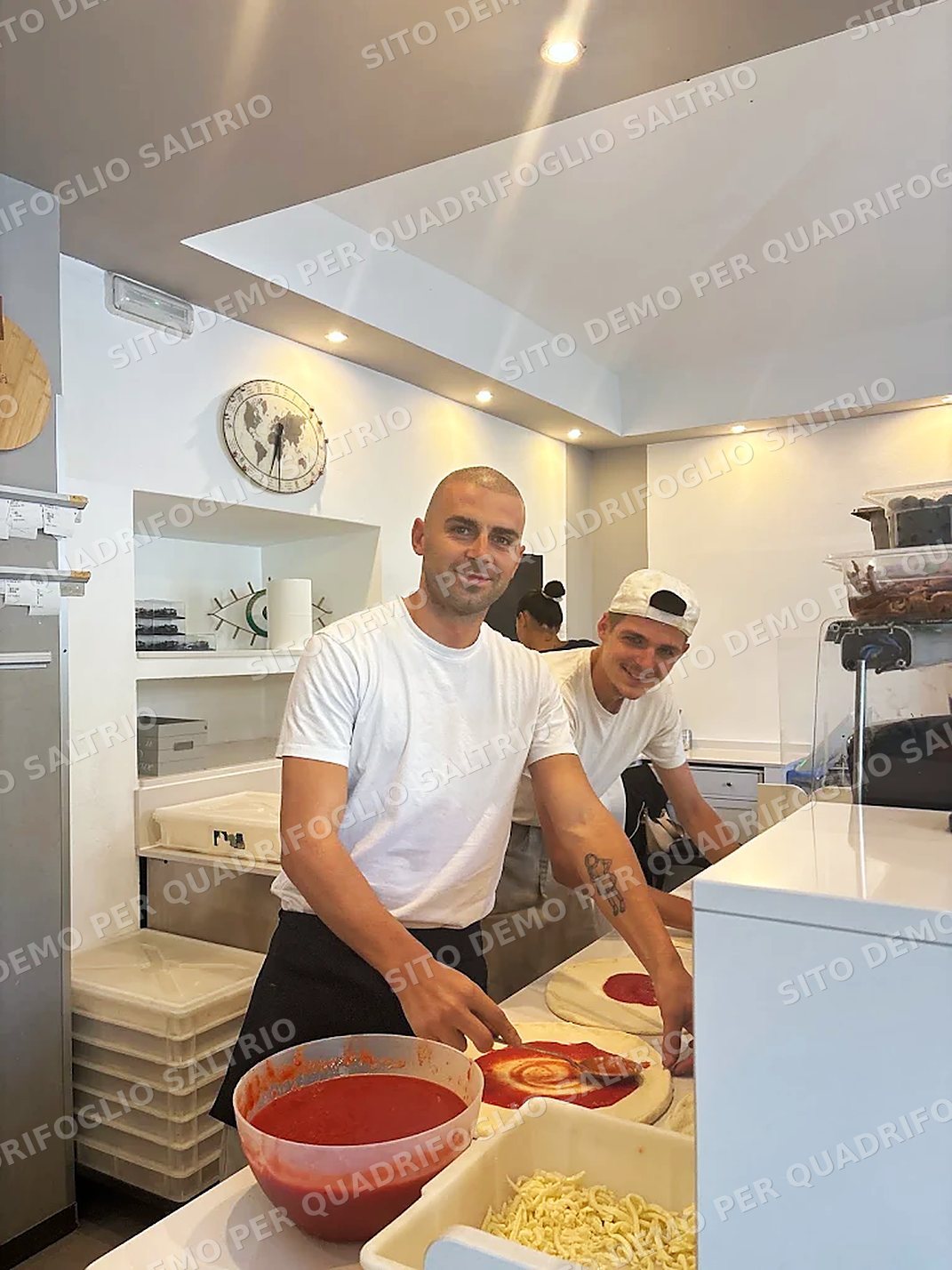 I pizzaioli di Quadrifoglio al banco mentre stendono il pomodoro sulle pizze